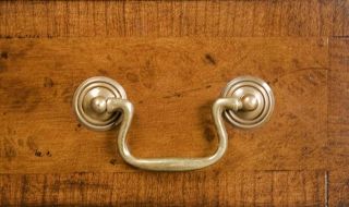 Solid brass swan neck pulls adorn the burl walnut drawer fronts.